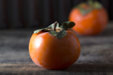 放在暗黑木板上的多个新鲜成熟的柿子俯拍特写