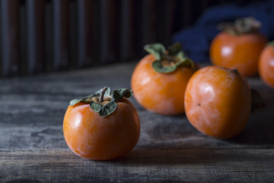 放在暗黑木板上的多个新鲜成熟的柿子俯拍特写
