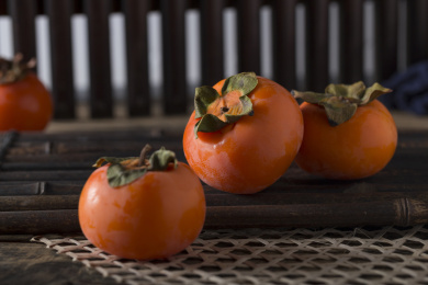 放在暗黑木板上的多个新鲜成熟的柿子俯拍特写