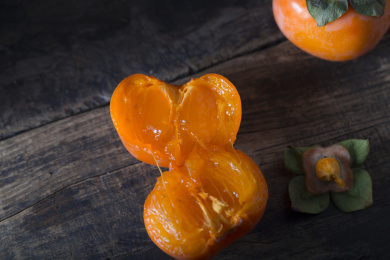 放在暗黑木板上的多个新鲜成熟的柿子俯拍特写