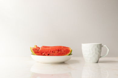 白色的水杯与白色盘子里的西瓜