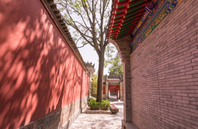 中国寺庙里一条狭长的通道，一面是红色砖墙，一面是青砖盖成的寺庙