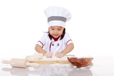 穿着厨师服的小女孩做面食手工揉面和面