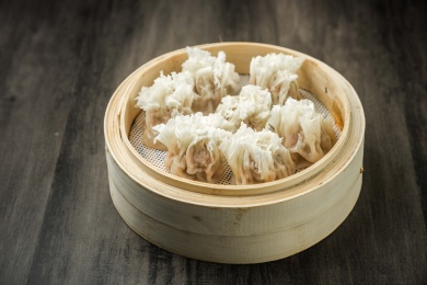 暗色木纹桌上放着一屉鲜肉烧麦