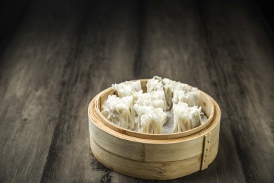 暗色木纹桌上放着一屉烧麦