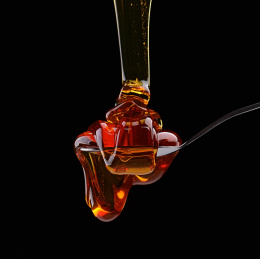 黑色背景中流动的琥珀色枣花蜂蜜