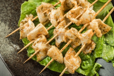 暗色木纹桌面上放着一盘烤熟的牛板肠串