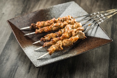 暗色木纹桌上放着一盘烤羊肉串
