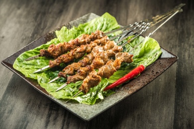 暗色木纹桌上放着一盘烤羊肉串