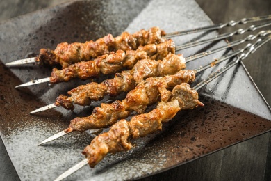 暗色木纹桌上放着一盘烤羊肉串