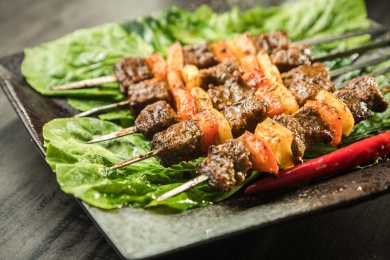 暗色木纹桌上放着一盘双椒牛肉串