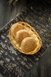 暗色木纹桌上放着三块芝麻酱烧饼