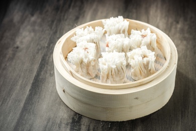 棕色木纹桌面上放着一笼烧麦