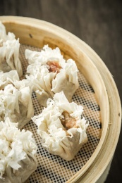 棕色木纹桌面上放着一笼烧麦