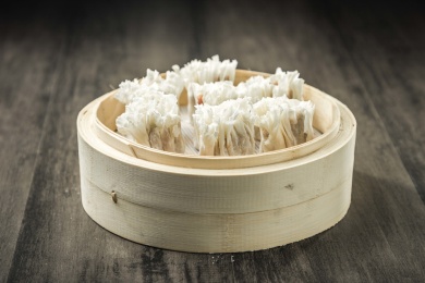 棕色木纹桌面上放着一笼烧麦