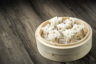 棕色木纹桌面上放着一笼烧麦