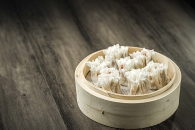 棕色木纹桌面上放着一笼烧麦