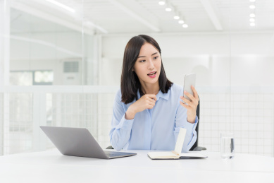 年轻的商务女性在办公室使用智能手机