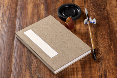 传统方法装裱的册页摆放在桌面上旁边放有文房四宝