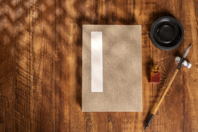 传统方法装裱的册页摆放在桌面上旁边放有文房四宝