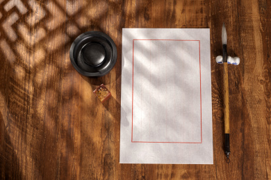 窗影下的桌面上摆放着中式信纸和毛笔等文房四宝