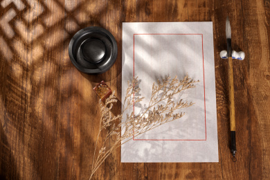 窗影下的桌面上摆放着中式信纸和毛笔等文房四宝