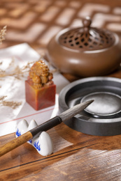 窗影下的桌面上摆放着中式信纸和毛笔等文房四宝