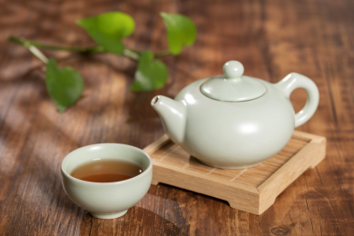 窗影下的桌面上摆放着汝瓷茶壶茶杯与绿萝