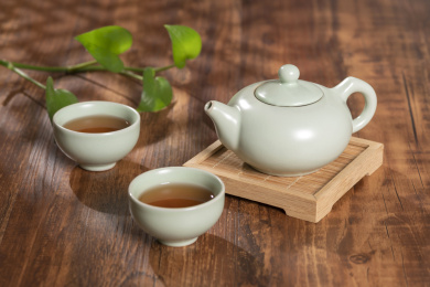 窗影下的桌面上摆放着汝瓷茶壶茶杯与绿萝