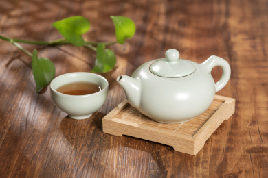窗影下的桌面上摆放着汝瓷茶壶茶杯与绿萝