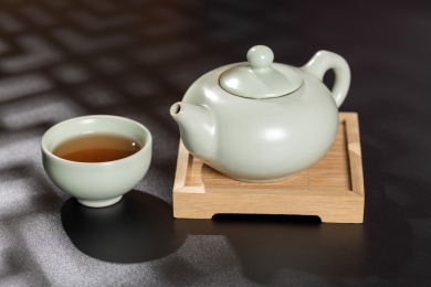 窗影下的桌面上摆放着汝瓷茶壶茶杯与绿萝