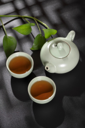 窗影下的桌面上摆放着汝瓷茶壶茶杯与绿萝