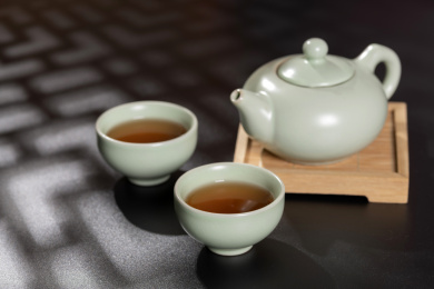 窗影下的桌面上摆放着汝瓷茶壶茶杯与绿萝