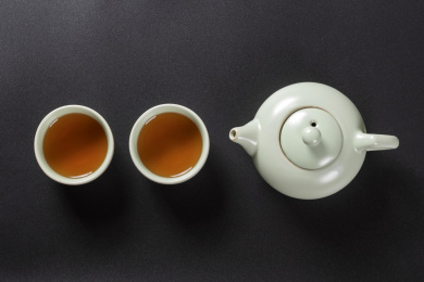 窗影下的桌面上摆放着汝瓷茶壶茶杯与绿萝