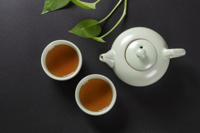 窗影下的桌面上摆放着汝瓷茶壶茶杯与绿萝