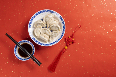 传统美食水饺盛放在青花碟子中摆放在喜庆的洒金红色背景上