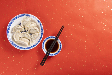 传统美食水饺盛放在青花碟子中摆放在喜庆的洒金红色背景上