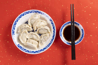 传统美食水饺盛放在青花碟子中摆放在喜庆的洒金红色背景上