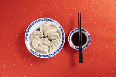 传统美食水饺盛放在青花碟子中摆放在喜庆的洒金红色背景上