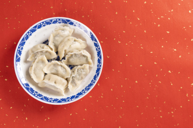 传统美食水饺盛放在青花碟子中摆放在喜庆的洒金红色背景上