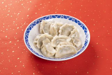 传统美食水饺盛放在青花碟子中摆放在喜庆的洒金红色背景上