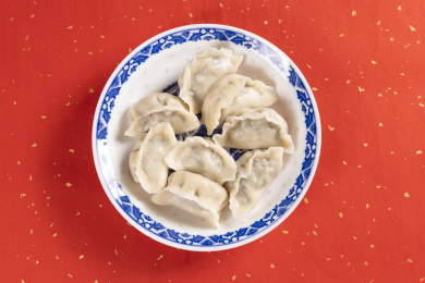 传统美食水饺盛放在青花碟子中摆放在喜庆的洒金红色背景上