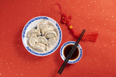 传统美食水饺盛放在青花碟子中摆放在喜庆的洒金红色背景上