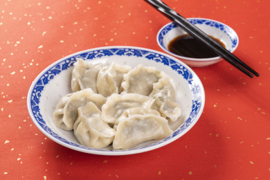 传统美食水饺盛放在青花碟子中摆放在喜庆的洒金红色背景上