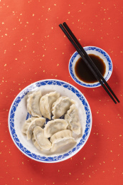 传统美食水饺盛放在青花碟子中摆放在喜庆的洒金红色背景上