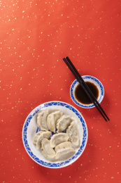 传统美食水饺盛放在青花碟子中摆放在喜庆的洒金红色背景上