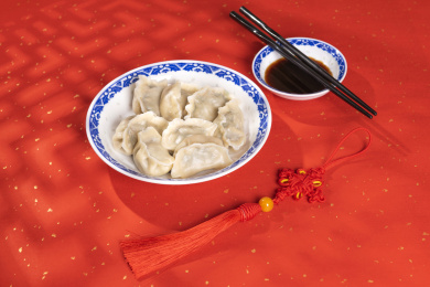 传统美食水饺盛放在青花碟子中摆放在喜庆的洒金红色背景上