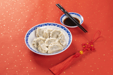 传统美食水饺盛放在青花碟子中摆放在喜庆的洒金红色背景上