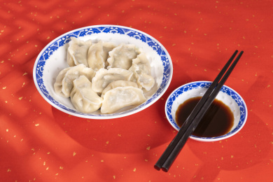 传统美食水饺盛放在青花碟子中摆放在喜庆的洒金红色背景上