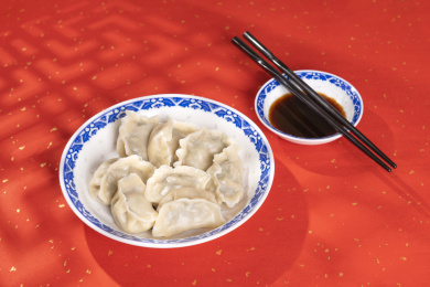 传统美食水饺盛放在青花碟子中摆放在喜庆的洒金红色背景上
